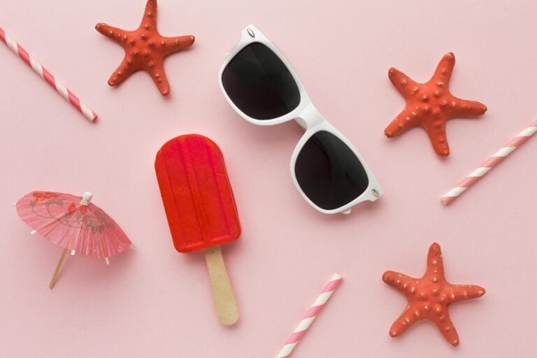 Beach-themed accessories including starfish, sunglasses, and popsicle on pink background.